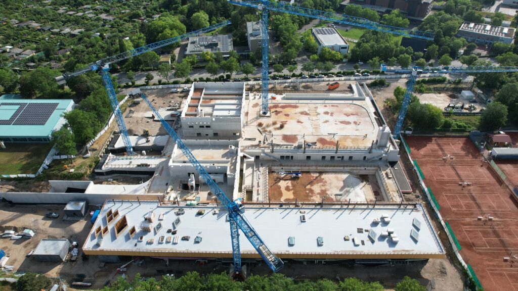 Luftaufnahme einer großen Baustelle mit mehreren blauen Baukränen
